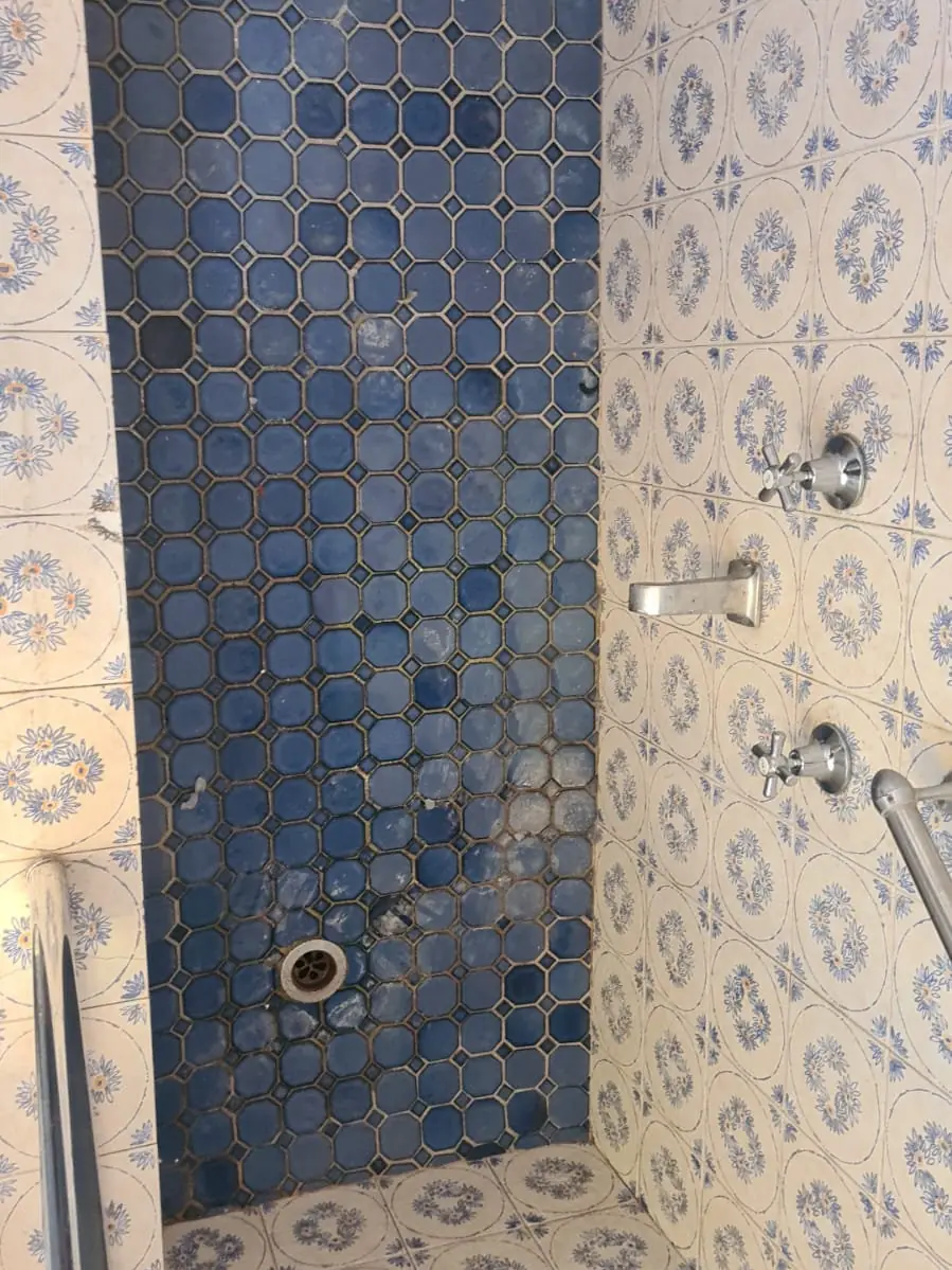 Before: Blue mosaic shower floor with dark stained patches