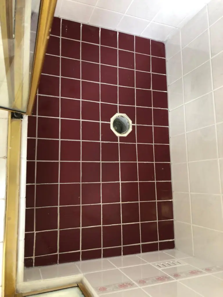 After: The same shower floor with the damaged area repaired and uniform grout (waste grate removed at the time of the photo)