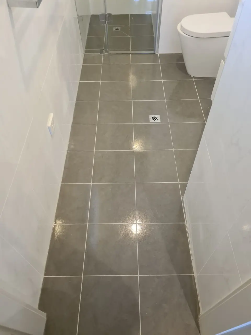 After: The same bathroom floor with bright renewed grout and a clean finish