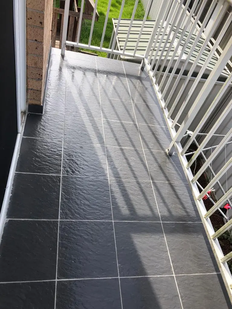 After: The same balcony with fresh light grout and a glossy sealed surface