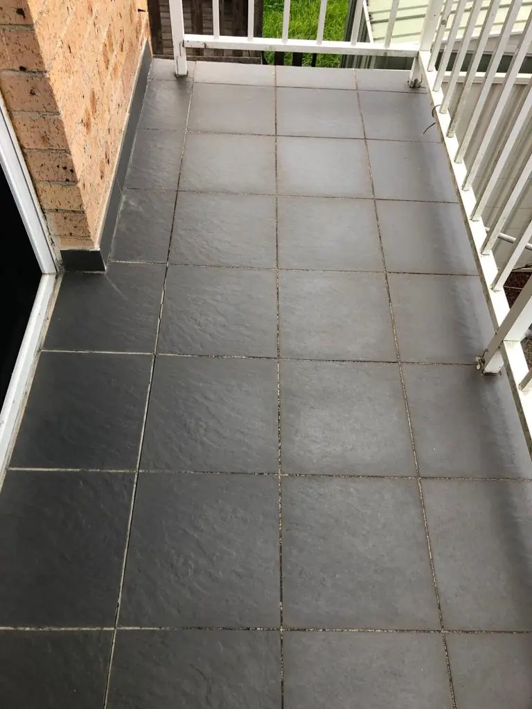 Before: Dark slate-look tiled balcony with a white balustrade, surface dull and grout discoloured