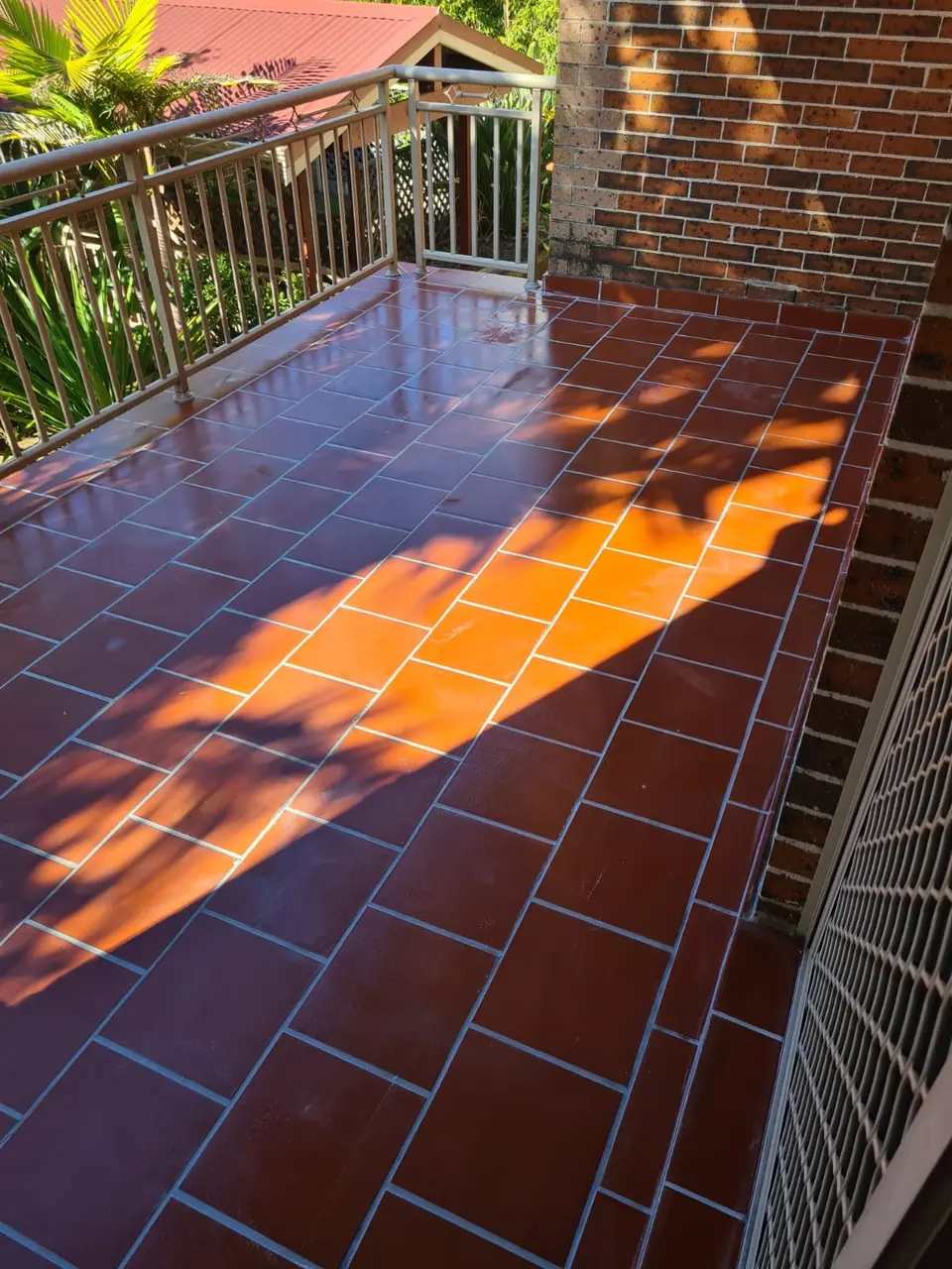 After: The same terracotta-tiled balcony with renewed grout and a glossy sealed finish